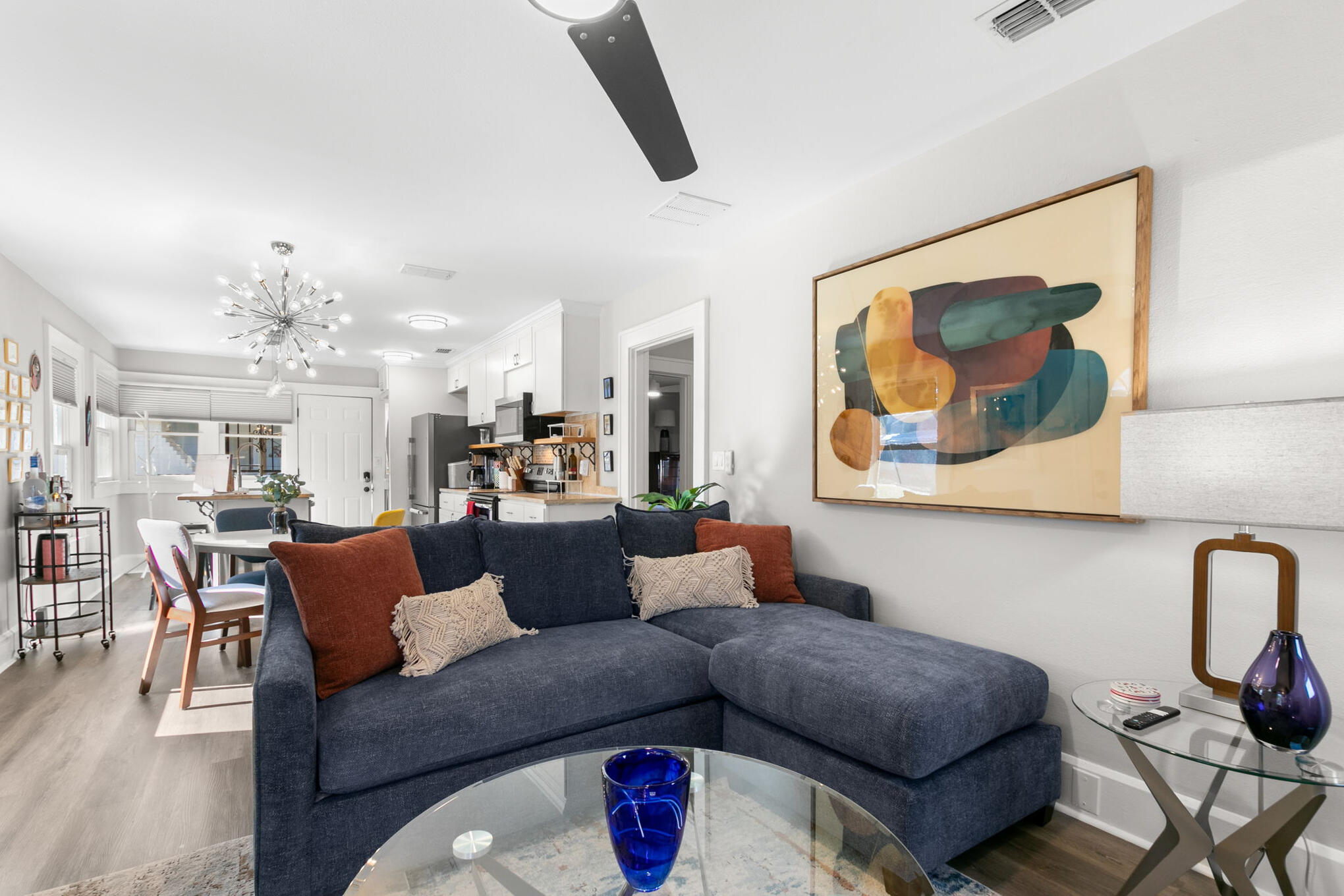 Ella House living room with sectional sofa, original artwork and open view to the kitchen