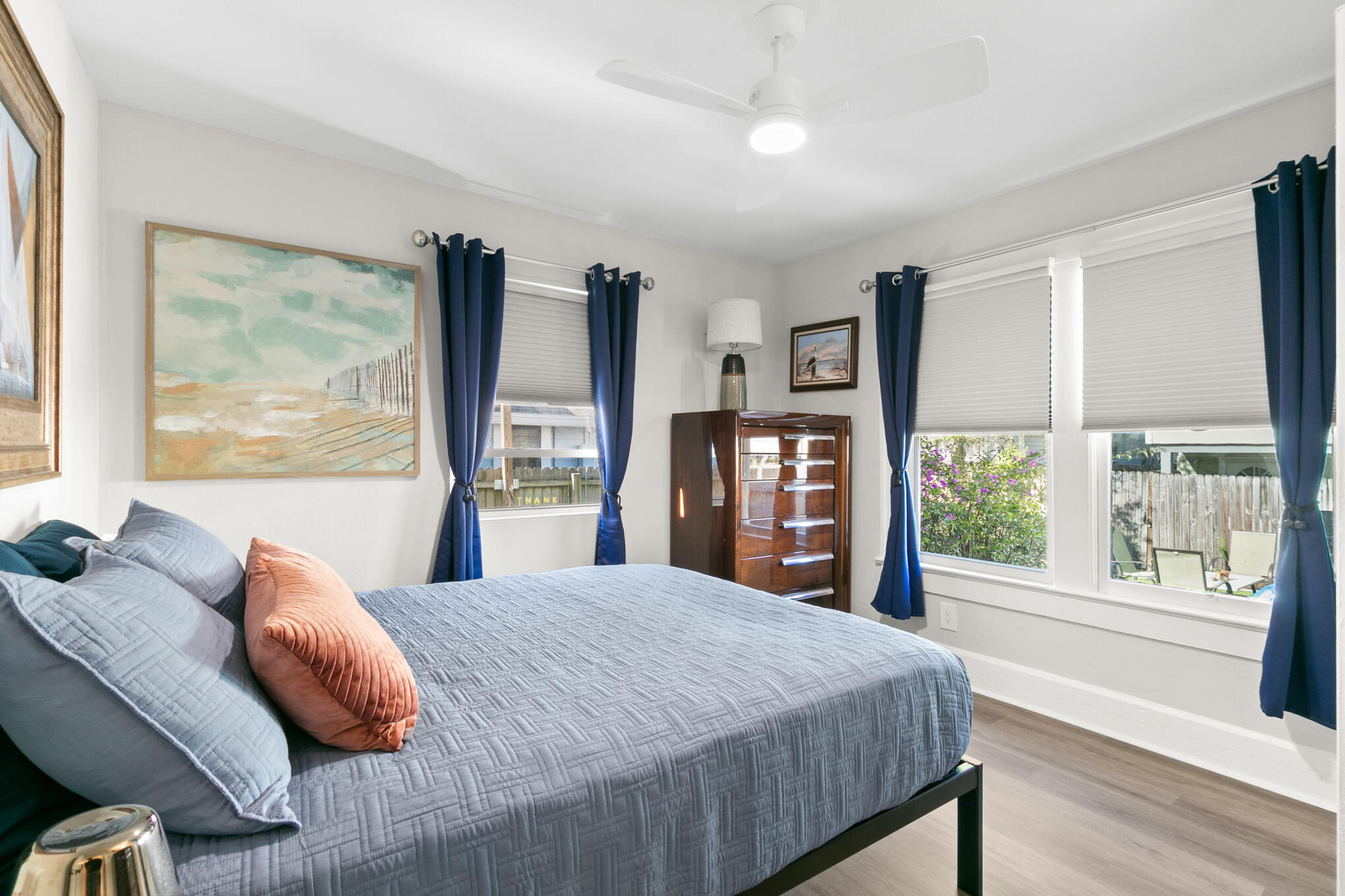 Ella House bedroom with ceiling fan, blue curtains and abundant natural light